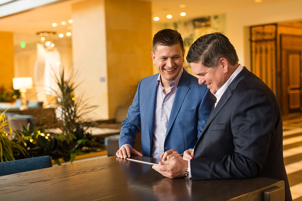 two agents standing up looking at an ipad