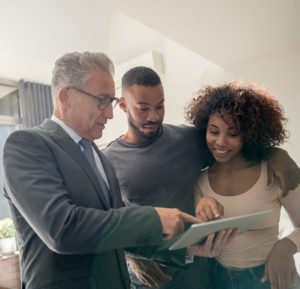 Real estate agent showing a property to a happy African American couple using a tablet computer â lifestyle concepts