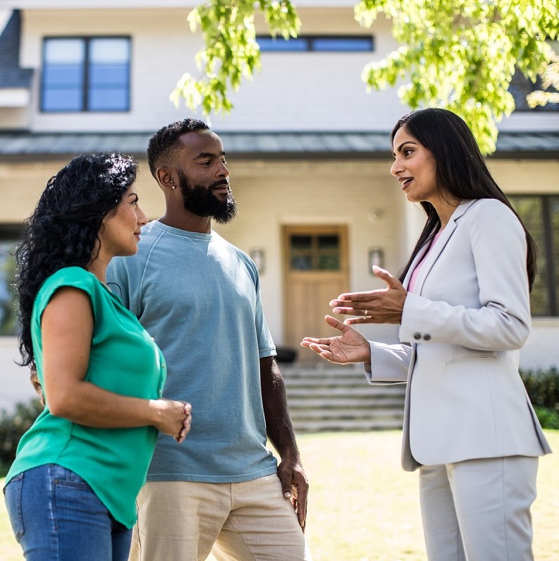 Couple meeting with real estate agent in front of home