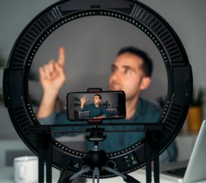 man recording himself on phone attached to ring light