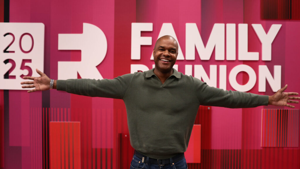 Attendee in front of Family Reunion 2025 sign in the Exhibit Hall.